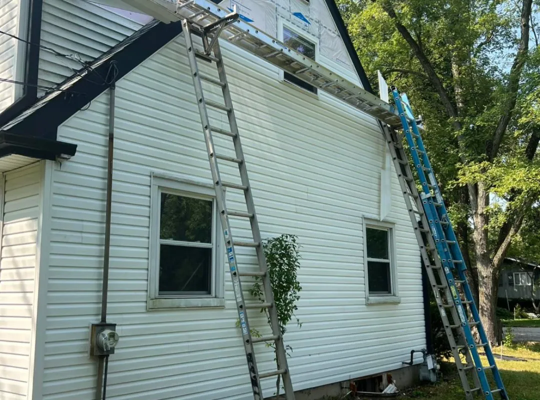 Crew replacing siding on a two-story home with ladders set up, Eau Claire WI